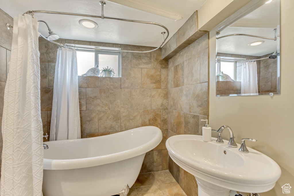 Full bath with tile walls, a healthy amount of sunlight, and a sink