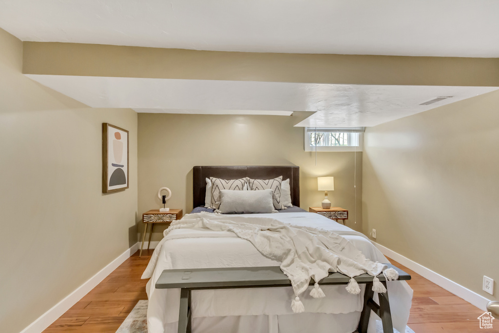 Bedroom with light wood finished floors, baseboards, and visible vents
