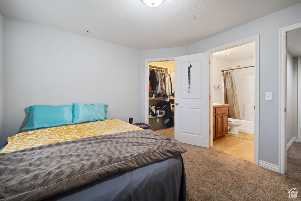 Bedroom featuring ensuite bathroom, light carpet, a closet, and a spacious closet