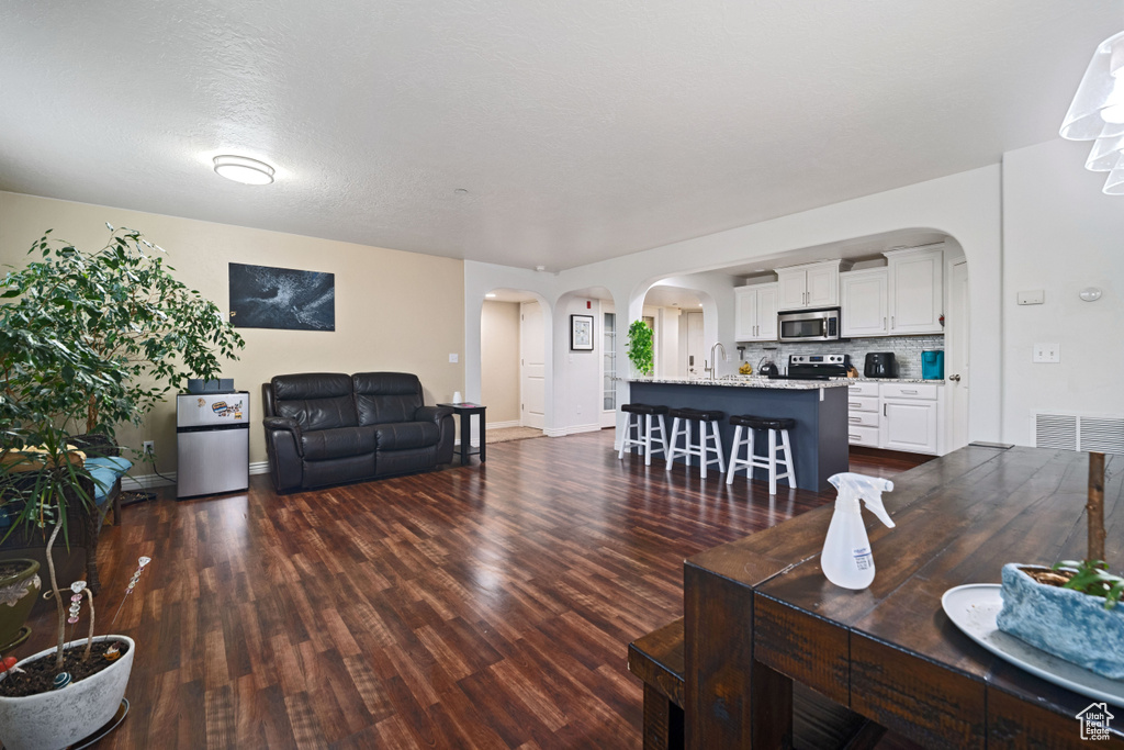 Living area featuring visible vents, baseboards, arched walkways, and dark wood-style floors