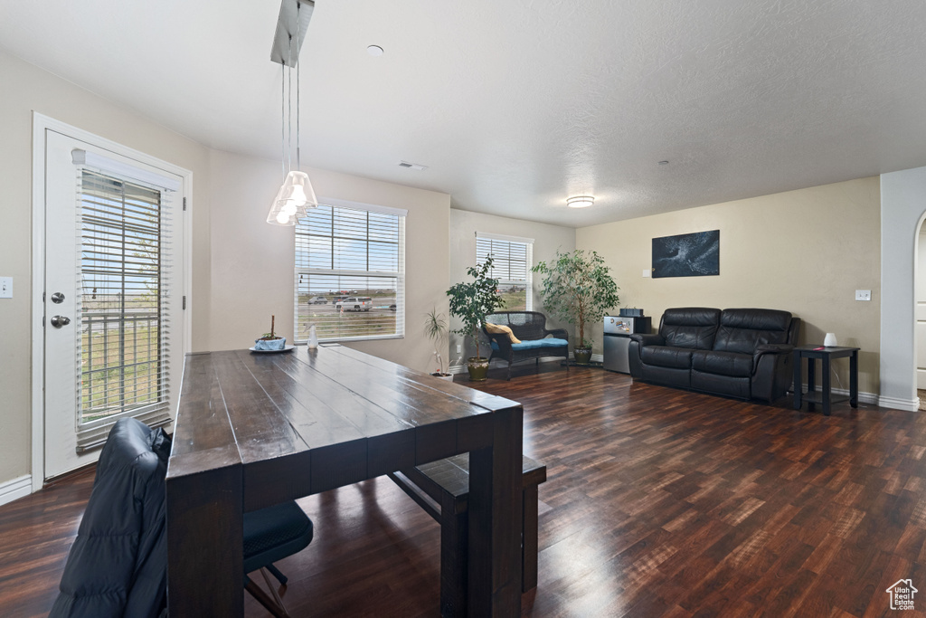 Dining room with dark wood-style flooring, baseboards, and arched walkways