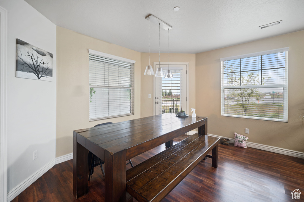 Dining space featuring a notable chandelier, baseboards, visible vents, and wood finished floors