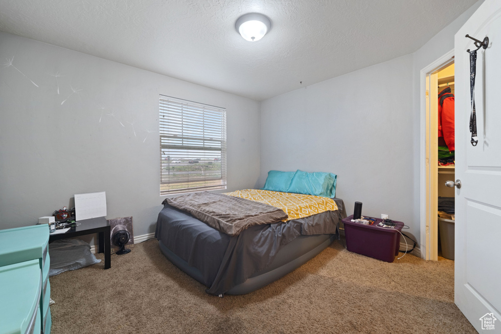 Bedroom with carpet, a textured ceiling, and baseboards
