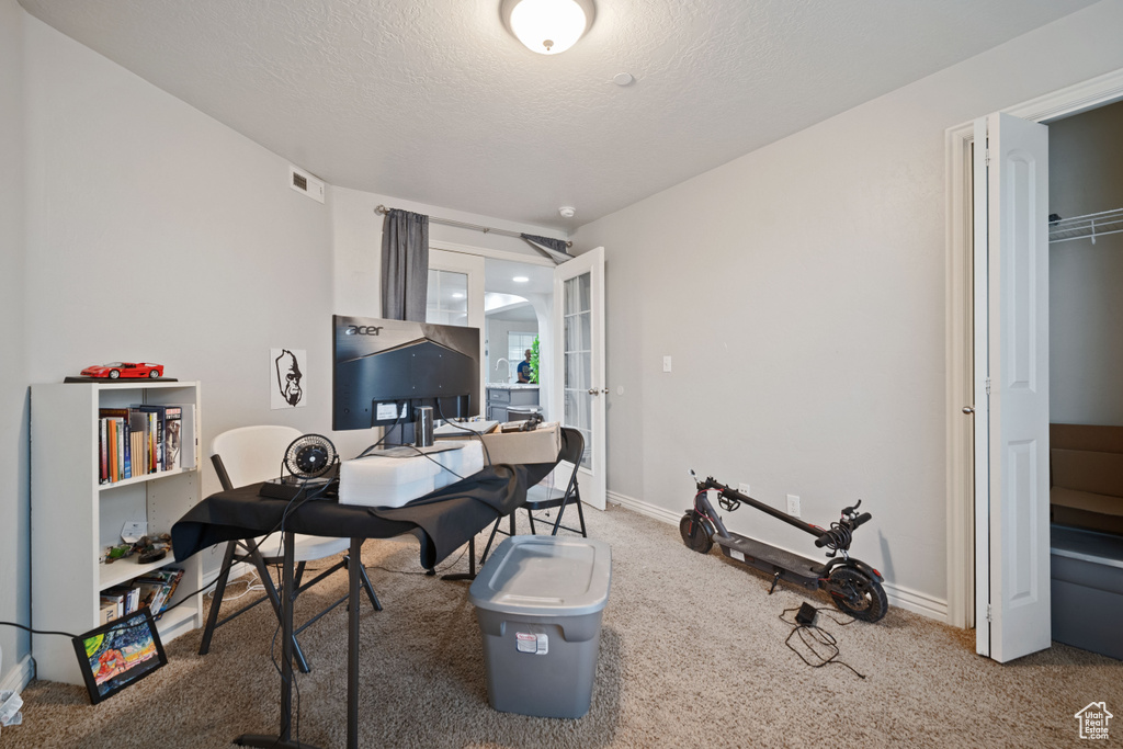 Carpeted office space featuring a textured ceiling, visible vents, french doors, and baseboards