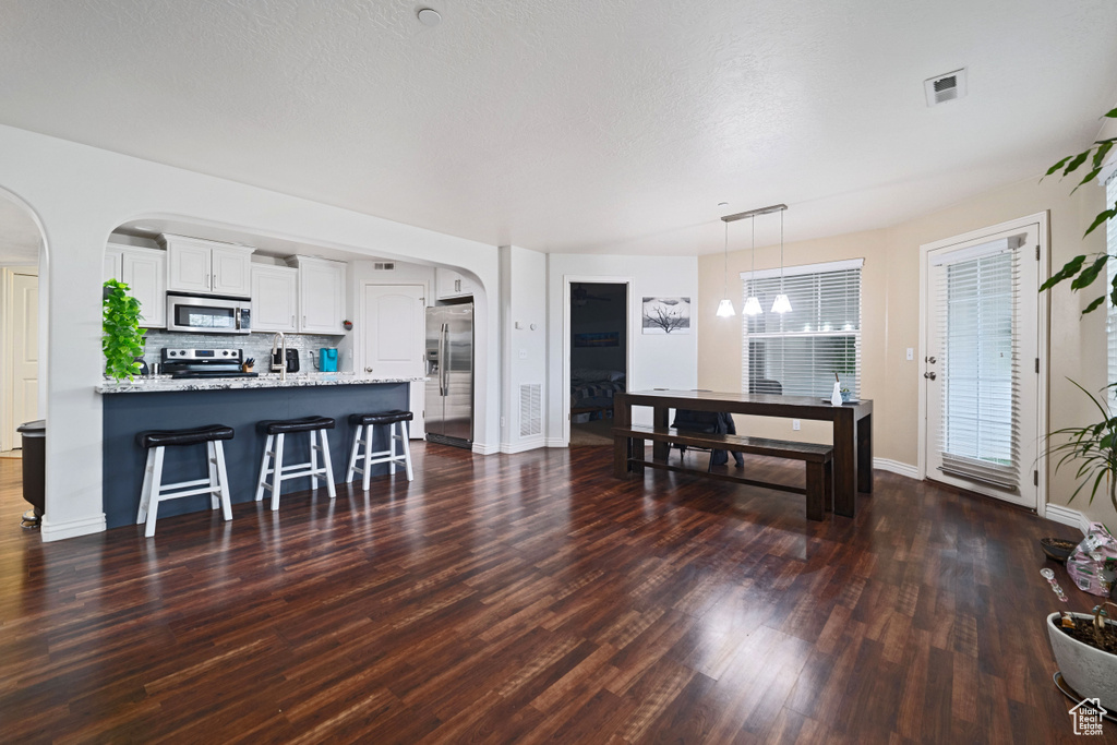 Living area with arched walkways, baseboards, visible vents, and wood finished floors