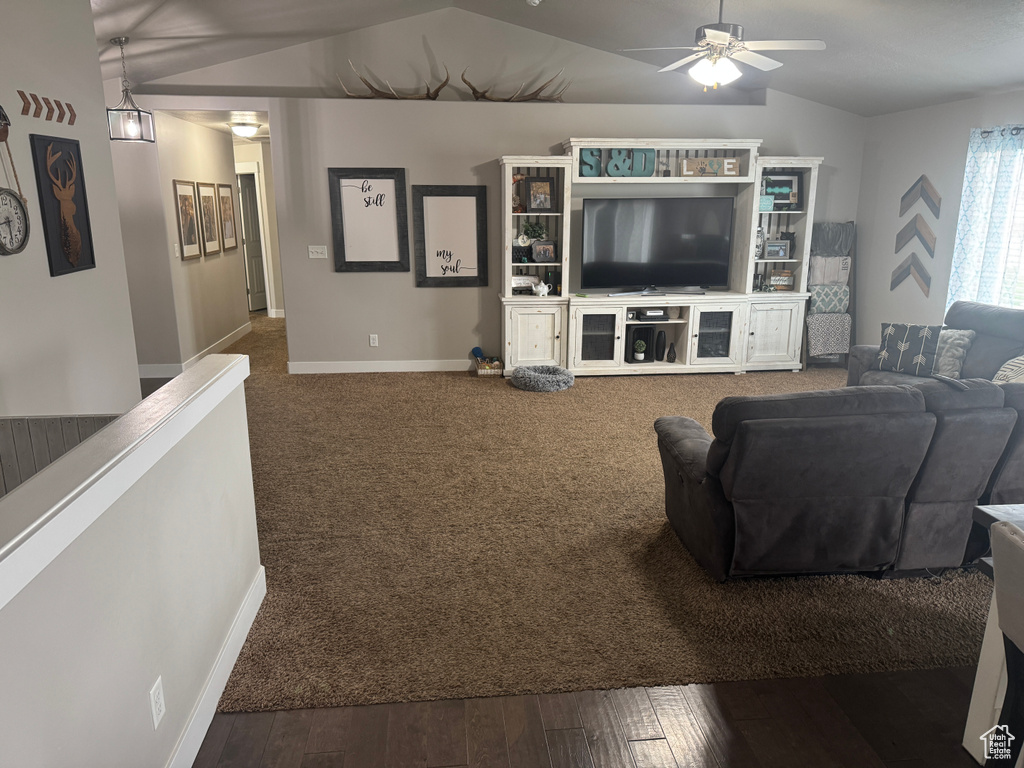 Living room featuring vaulted ceiling, baseboards, a ceiling fan, and dark wood-style floors