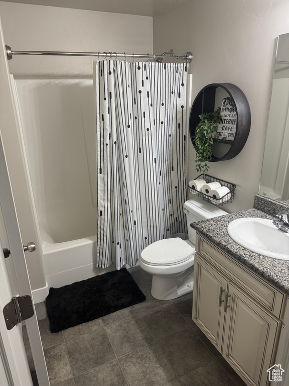 Full bath featuring toilet, shower / tub combo with curtain, stone finish flooring, and vanity