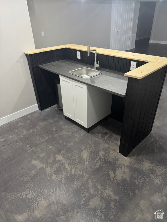 Kitchen featuring white cabinetry, baseboards, and a sink