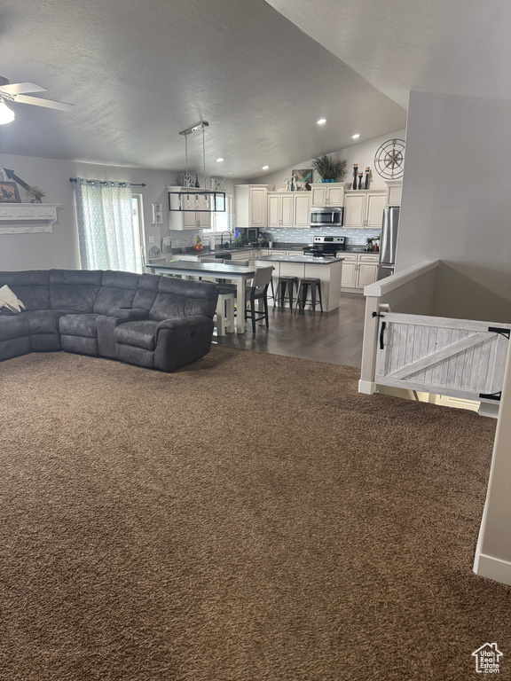 Living area featuring dark colored carpet, ceiling fan, and recessed lighting