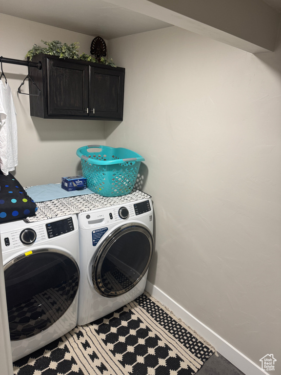 Laundry room featuring separate washer and dryer, cabinet space, and baseboards