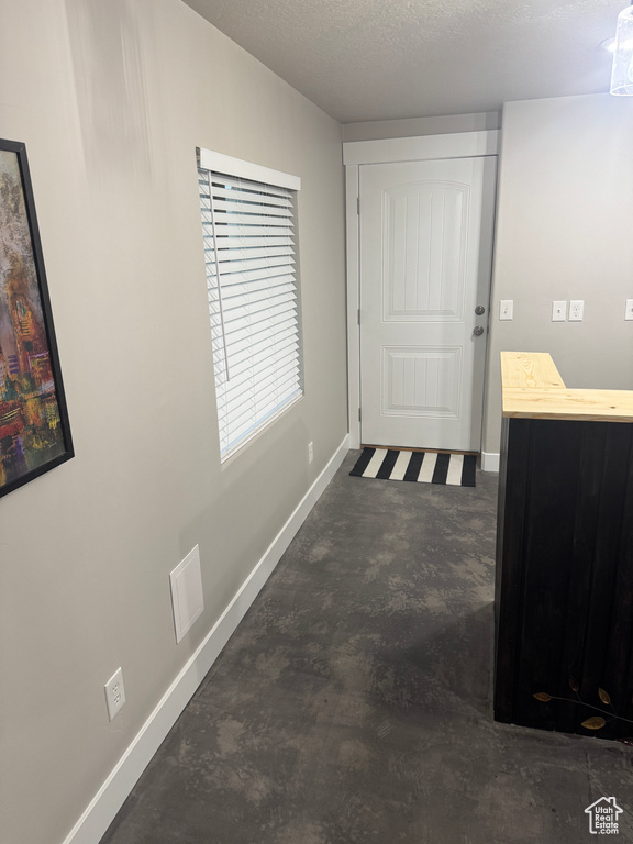 Corridor featuring a textured ceiling, baseboards, and concrete floors