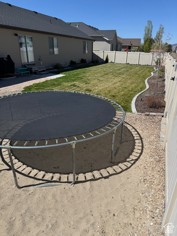 View of yard featuring a fenced backyard, a patio area, and a trampoline