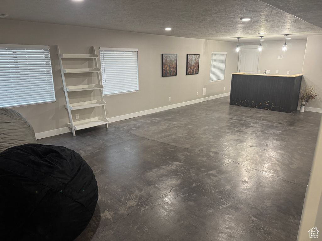 Basement with bar, a textured ceiling, baseboards, and recessed lighting