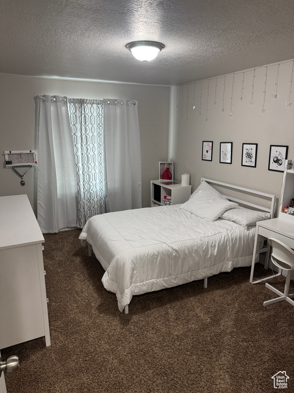 Bedroom with a textured ceiling and dark carpet