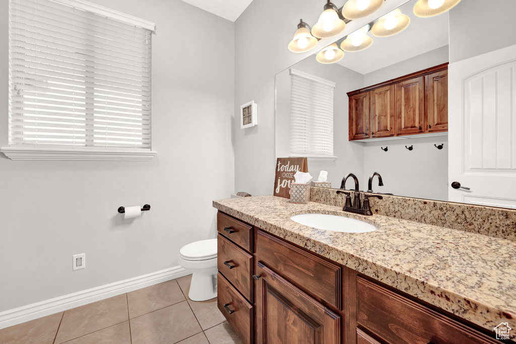 Bathroom with toilet, baseboards, tile patterned floors, and vanity