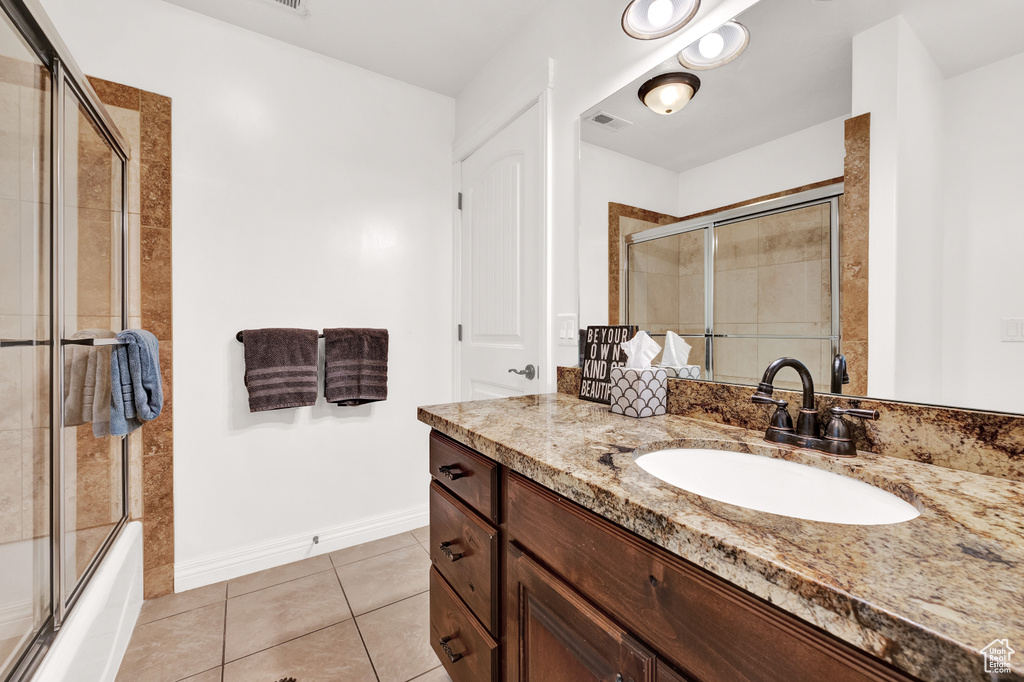 Bathroom with enclosed tub / shower combo, baseboards, visible vents, tile patterned floors, and vanity