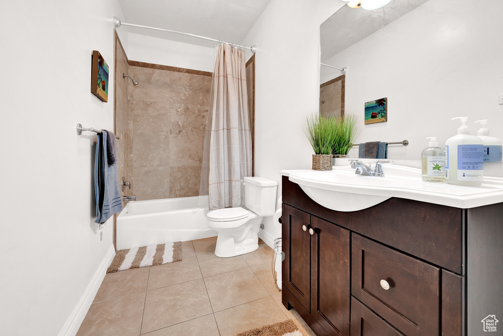 Full bathroom featuring shower / bath combo with shower curtain, baseboards, toilet, tile patterned flooring, and vanity