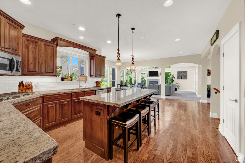 Kitchen featuring a sink, stainless steel appliances, open floor plan, a center island, and arched walkways