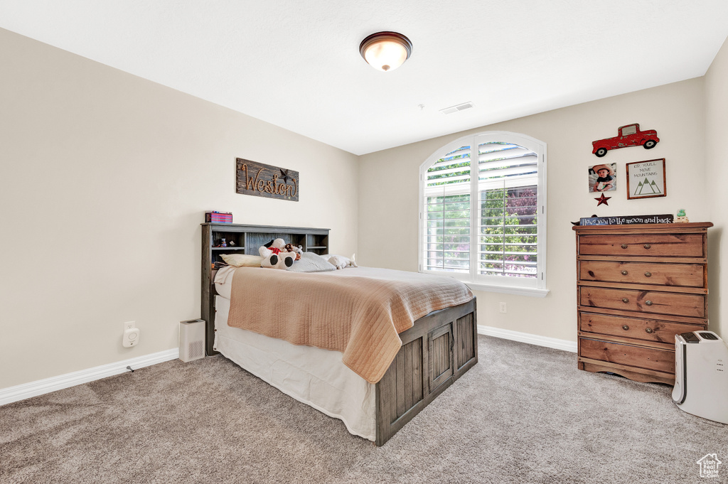 Carpeted bedroom featuring baseboards and visible vents