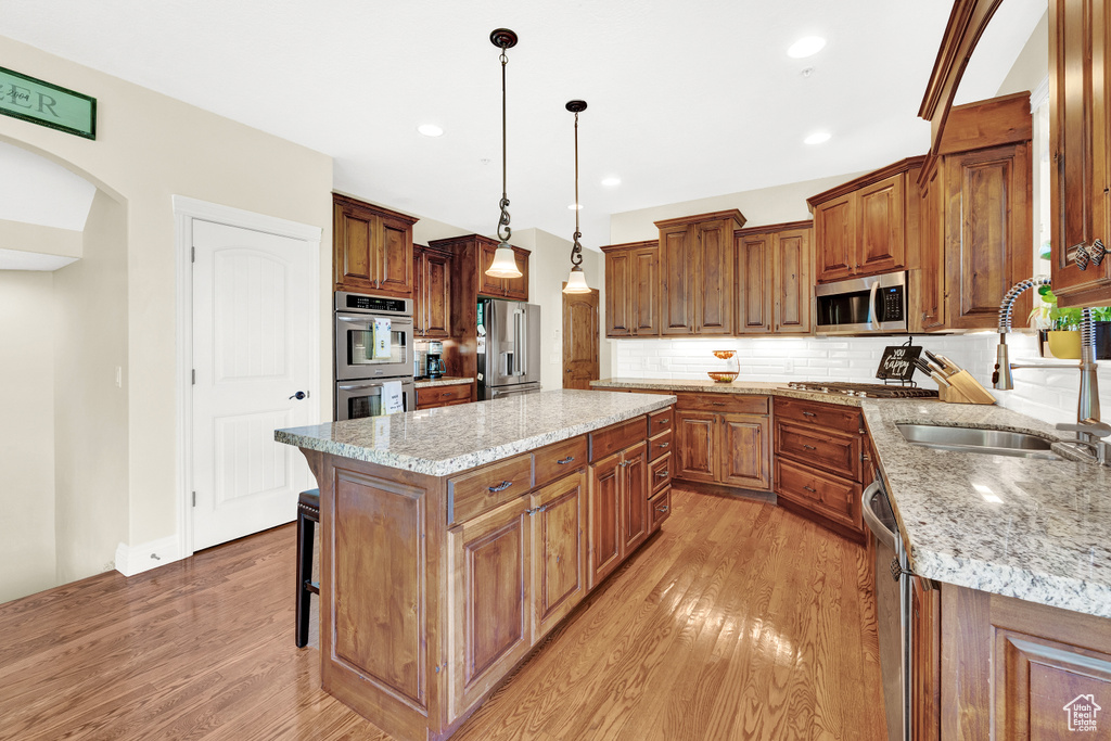 Kitchen with light wood finished floors, stainless steel appliances, a sink, and brown cabinets