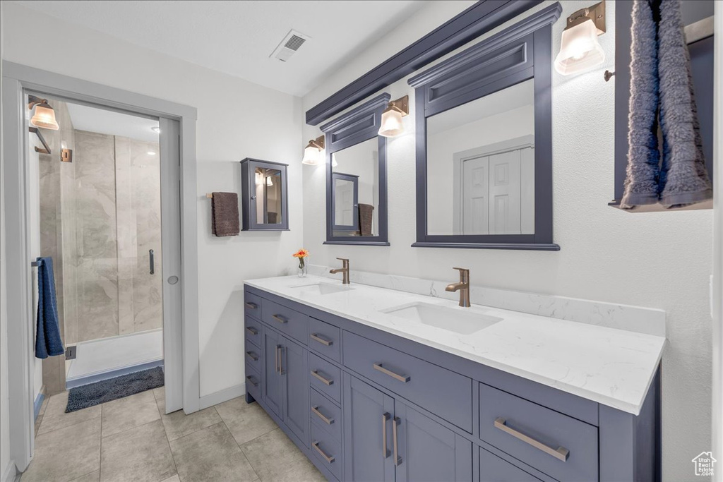Bathroom with a stall shower, visible vents, a sink, and double vanity