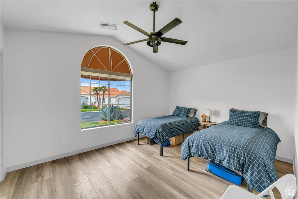 Bedroom with baseboards, visible vents, wood finished floors, and lofted ceiling
