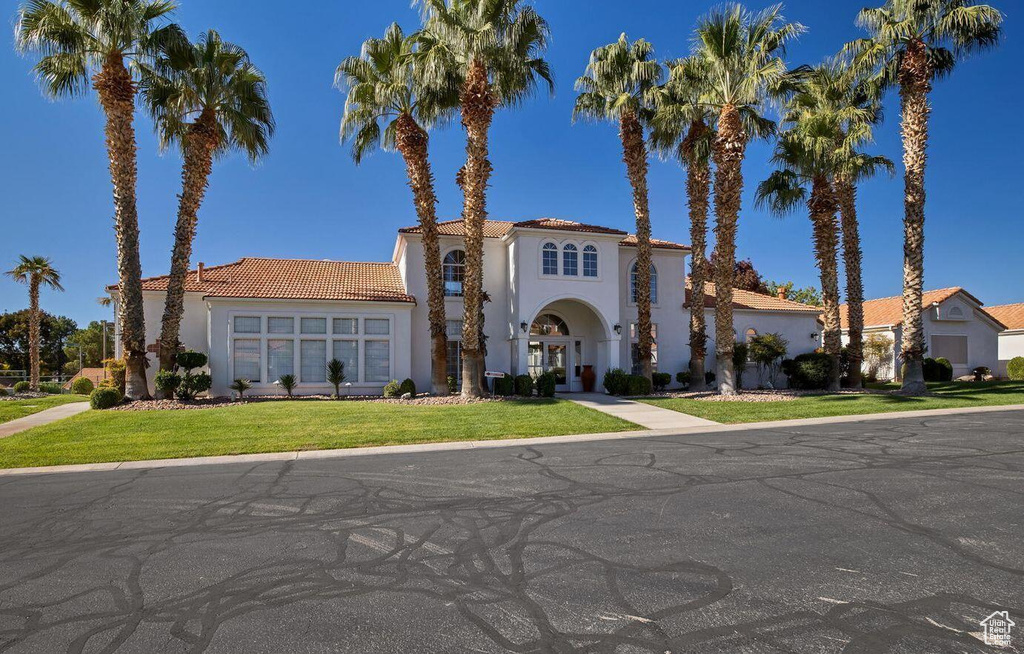 Mediterranean / spanish-style house featuring a front lawn, a tiled roof, and stucco siding