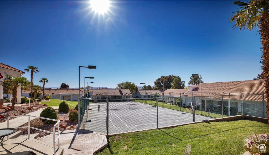 View of tennis court featuring a yard, fence, and a residential view