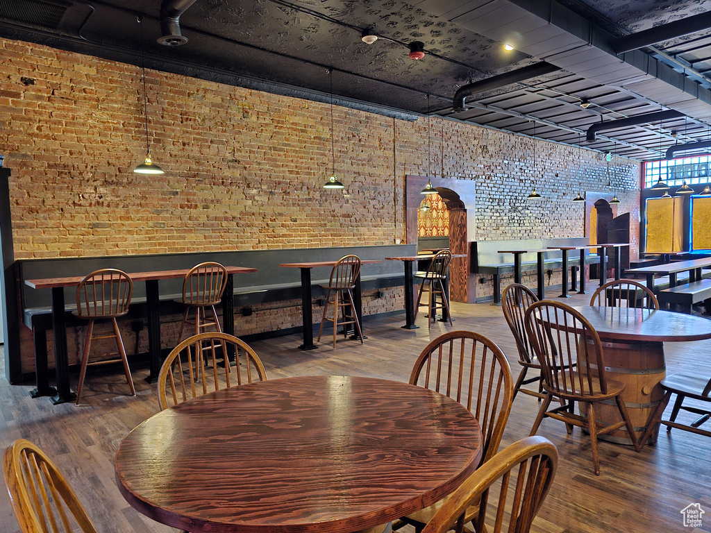 Dining room featuring arched walkways, brick wall, and wood finished floors