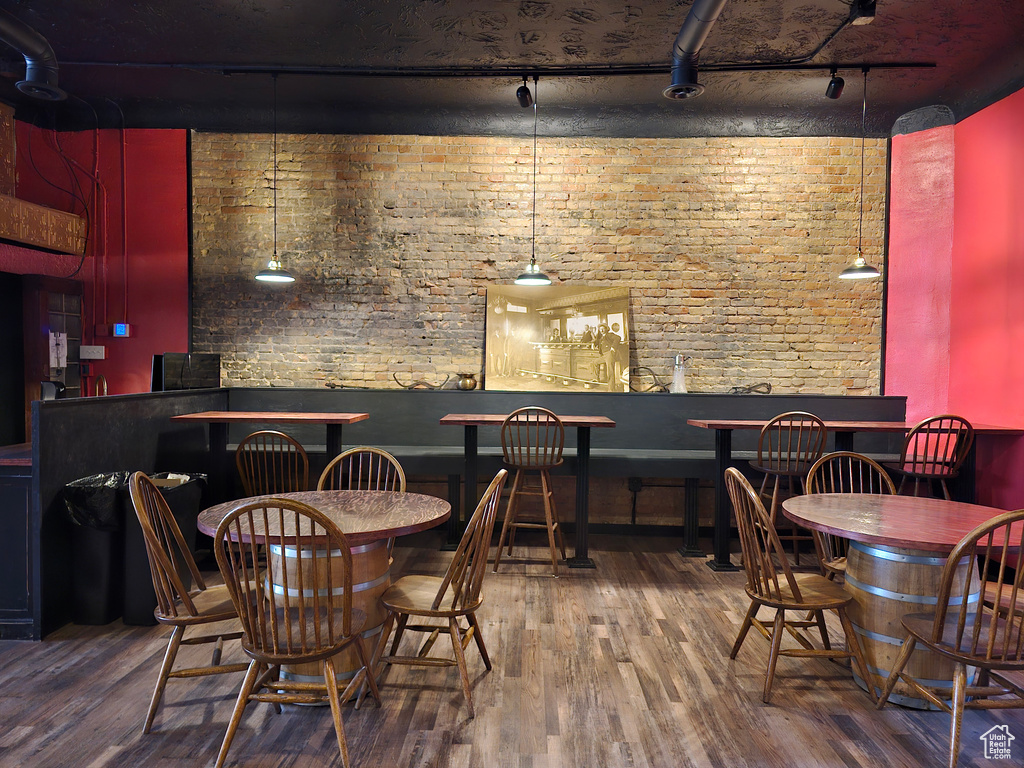 Dining space featuring track lighting, wood finished floors, and brick wall