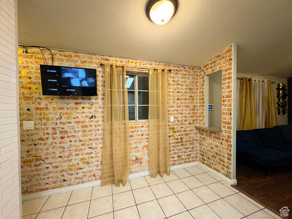 Interior space featuring a textured ceiling, baseboards, and brick wall