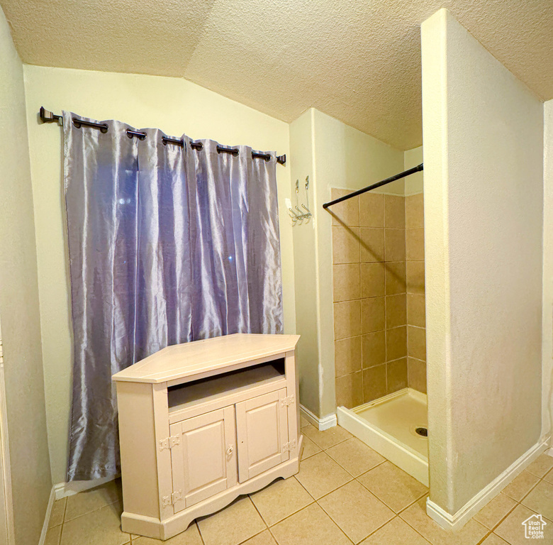 Full bath with a stall shower, tile patterned flooring, a textured ceiling, and baseboards
