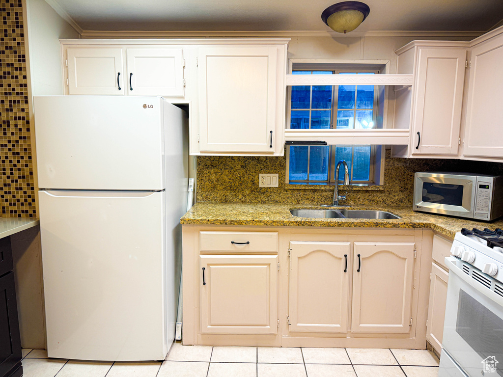 Kitchen with a sink, ornamental molding, white appliances, and light tile patterned floors