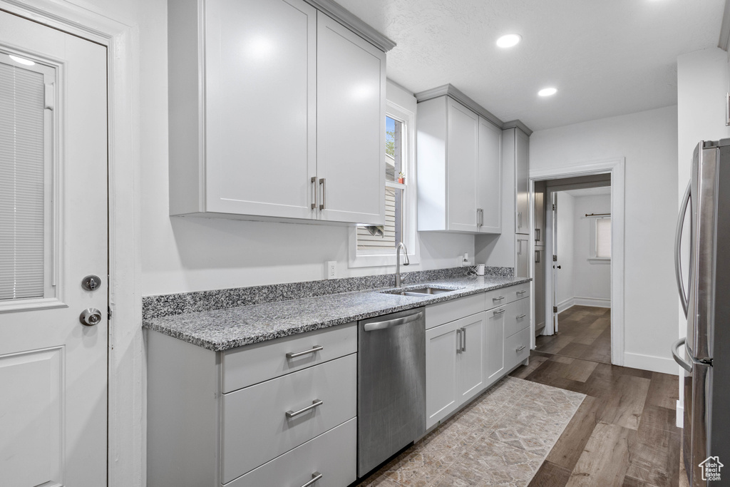 Kitchen with a sink, stainless steel appliances, recessed lighting, dark wood-style floors, and baseboards