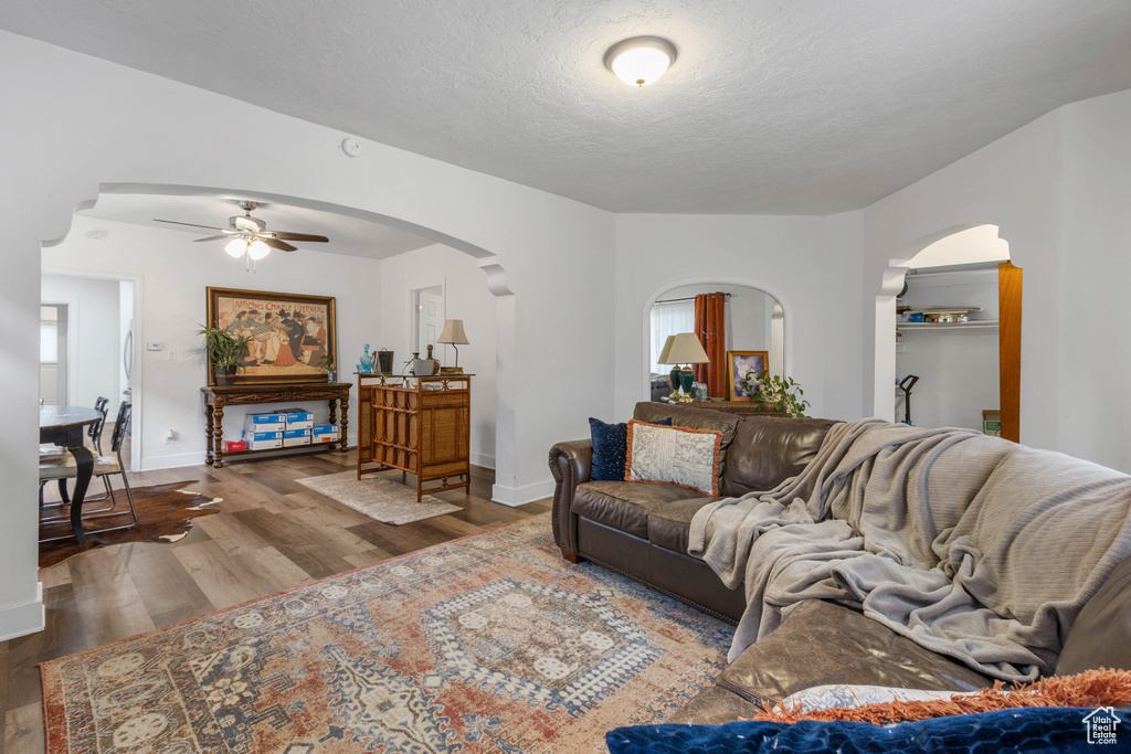 Living room with ceiling fan, arched walkways, baseboards, and wood finished floors