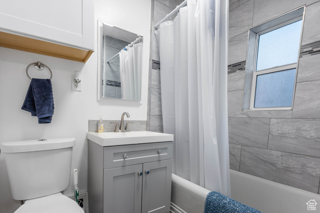 Full bath with vanity, toilet, and shower / bath combination with curtain