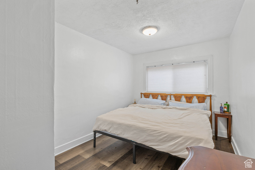 Bedroom with baseboards, a textured ceiling, and wood finished floors