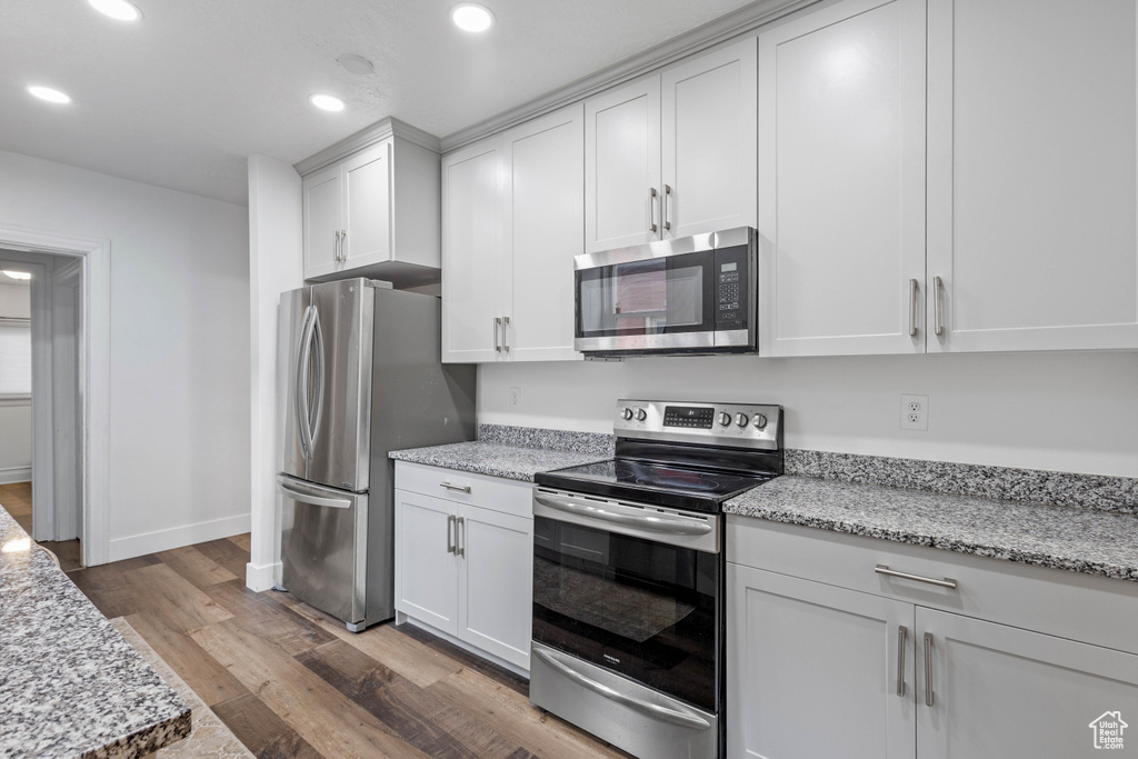 Kitchen featuring white cabinetry, recessed lighting, appliances with stainless steel finishes, and wood finished floors