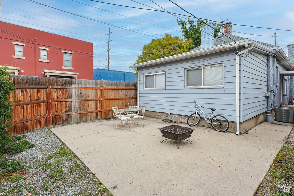 Rear view of property with a chimney, fence, cooling unit, a patio area, and a fire pit