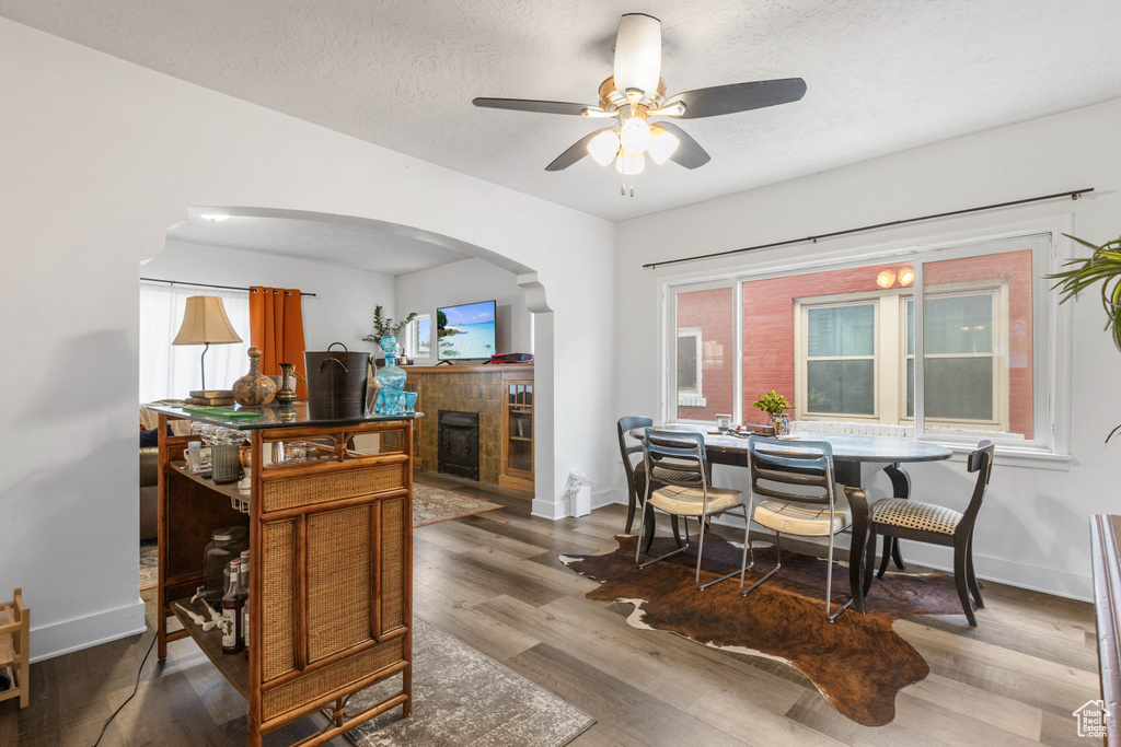 Dining area featuring arched walkways, a ceiling fan, baseboards, and wood finished floors