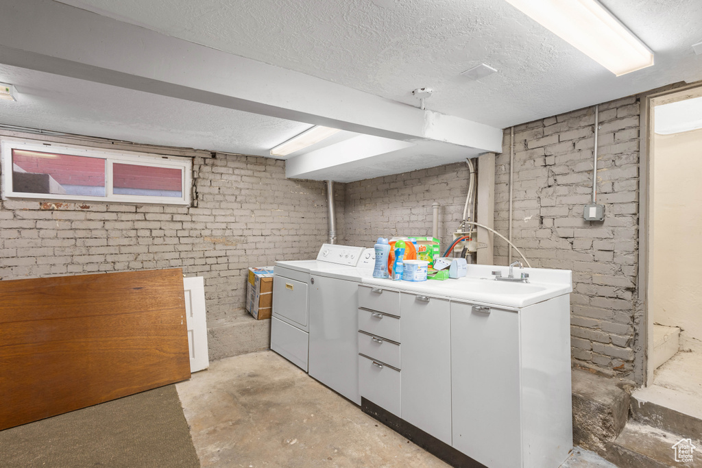 Laundry room with washing machine and clothes dryer, a sink, laundry area, and a textured ceiling