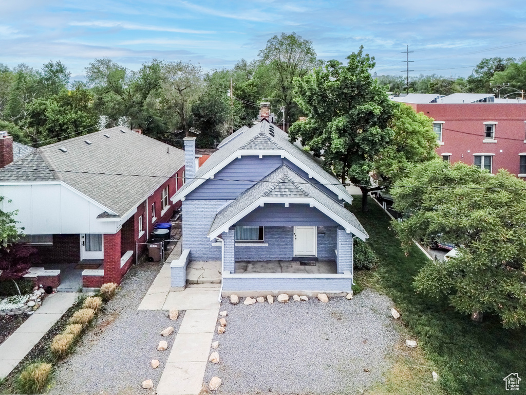 View of front of home featuring a shingled roof, brick siding, and a chimney