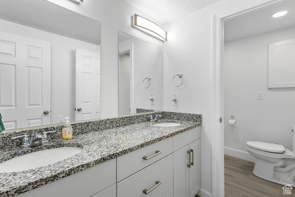 Bathroom featuring a sink, double vanity, toilet, and baseboards