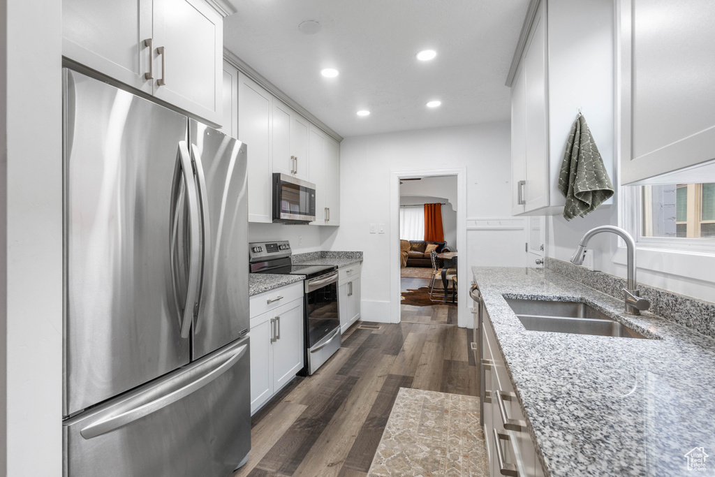 Kitchen featuring a sink, light stone counters, recessed lighting, dark wood-style floors, and appliances with stainless steel finishes