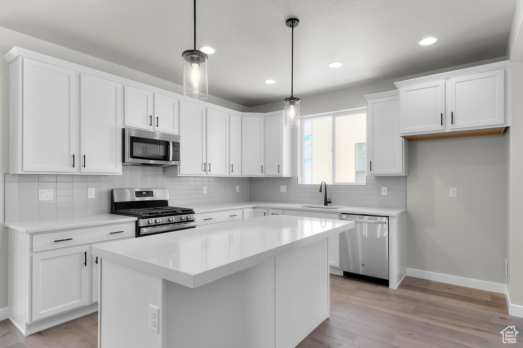 Kitchen with stainless steel appliances, a sink, light wood-style flooring, white cabinetry, and recessed lighting