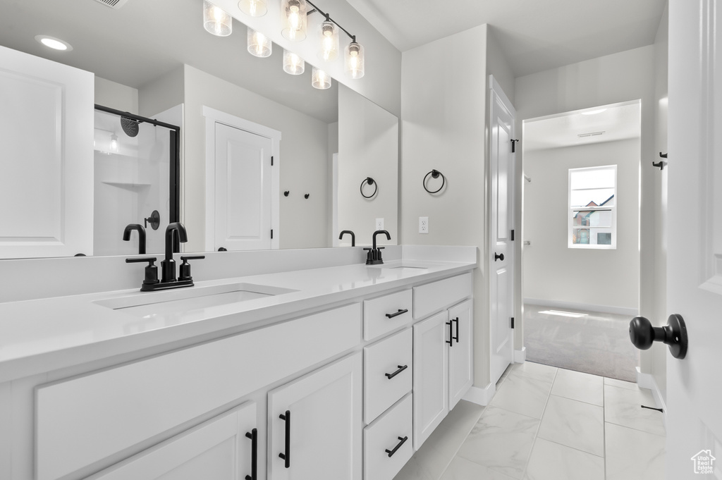 Bathroom with double vanity, marble finish flooring, an enclosed shower, and baseboards