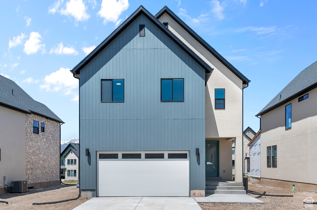 View of front of home featuring cooling unit, driveway, and a garage