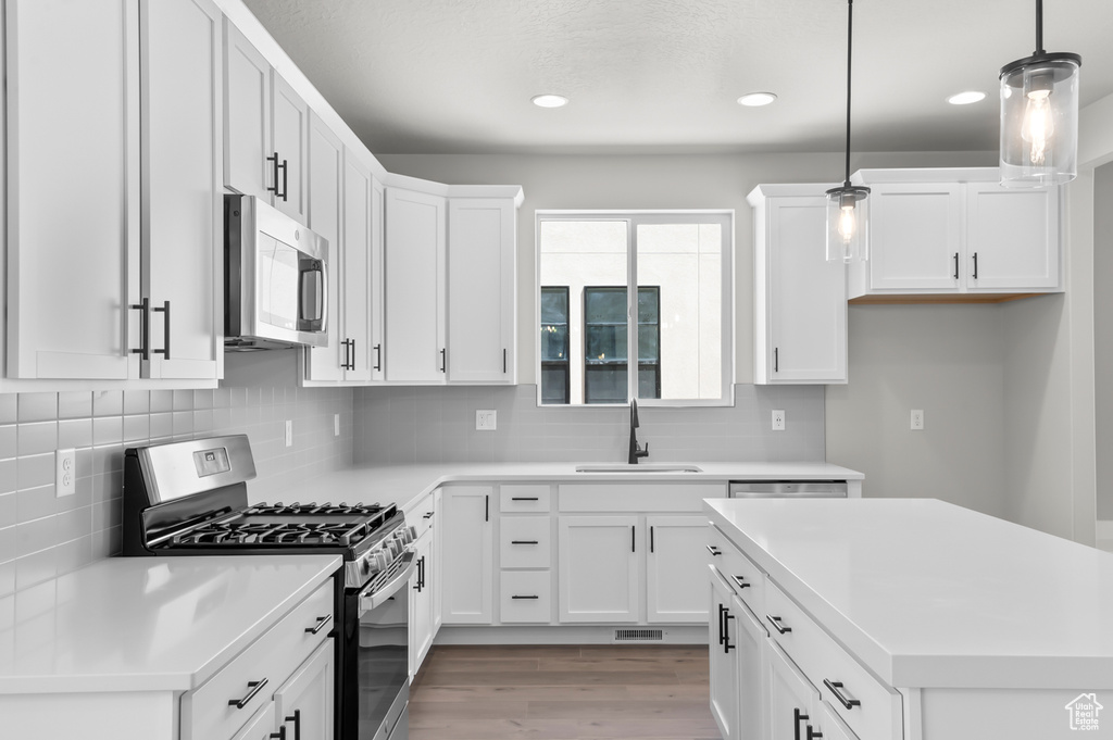 Kitchen featuring appliances with stainless steel finishes, a sink, recessed lighting, light wood-style flooring, and decorative backsplash