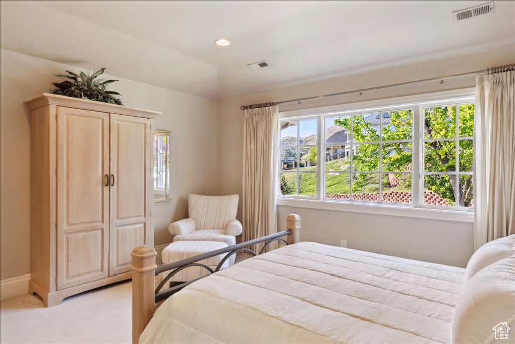 Bedroom with light colored carpet, visible vents, and multiple windows