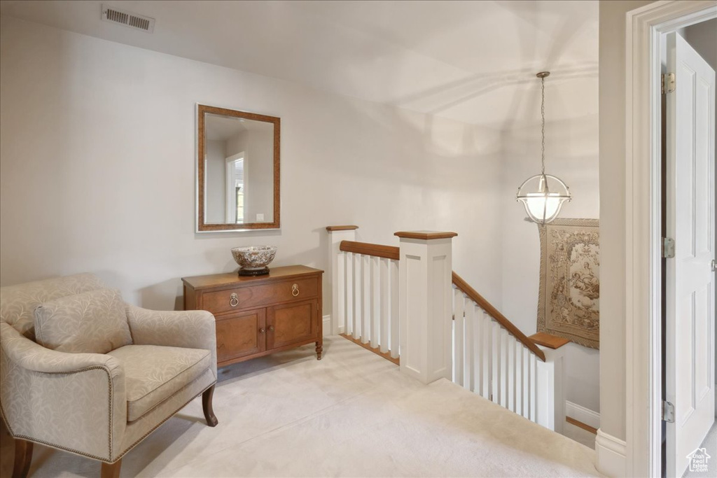 Sitting room with visible vents, an upstairs landing, baseboards, and light carpet
